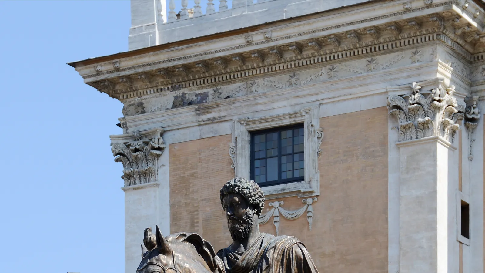 Bronze equestrian statue of Marcus Aurelius on the Capitoline Hill in Rome, framed against the Palazzo Senatorio.