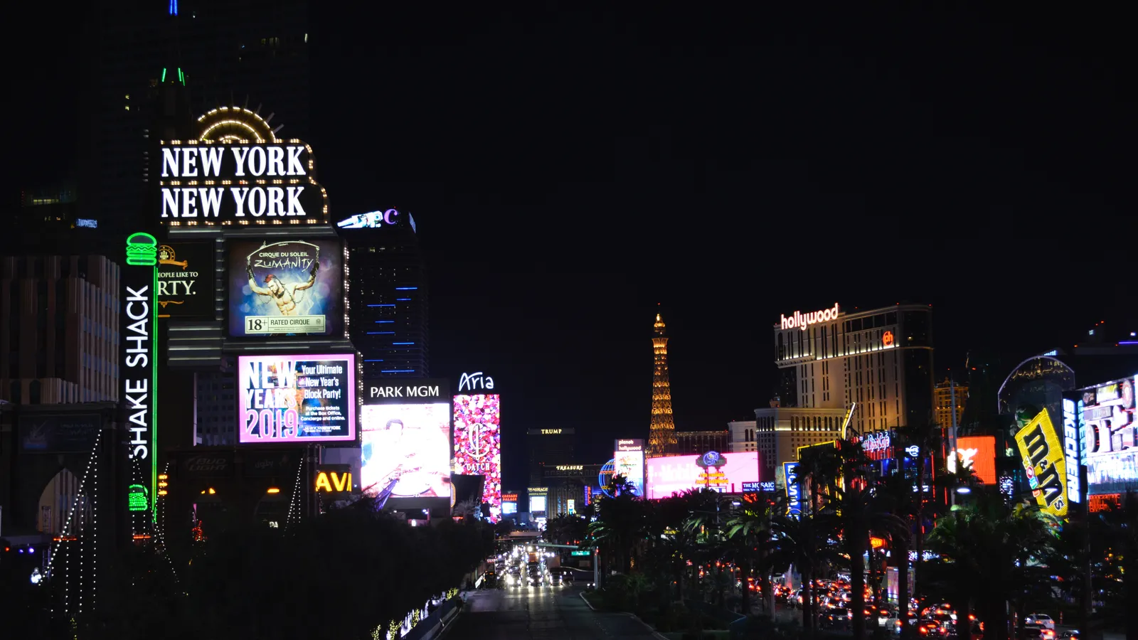 The Las Vegas Strip at night, with neon facades and a replica Eiffel Tower.