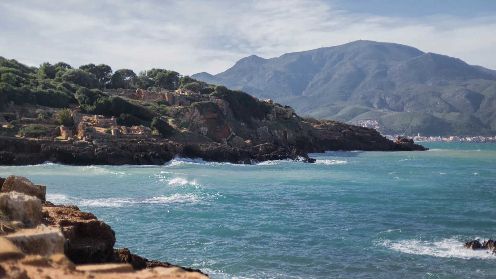 Roman ruins on the Mediterranean coast at Tipasa, Algeria, with stone walls and sea visible behind.