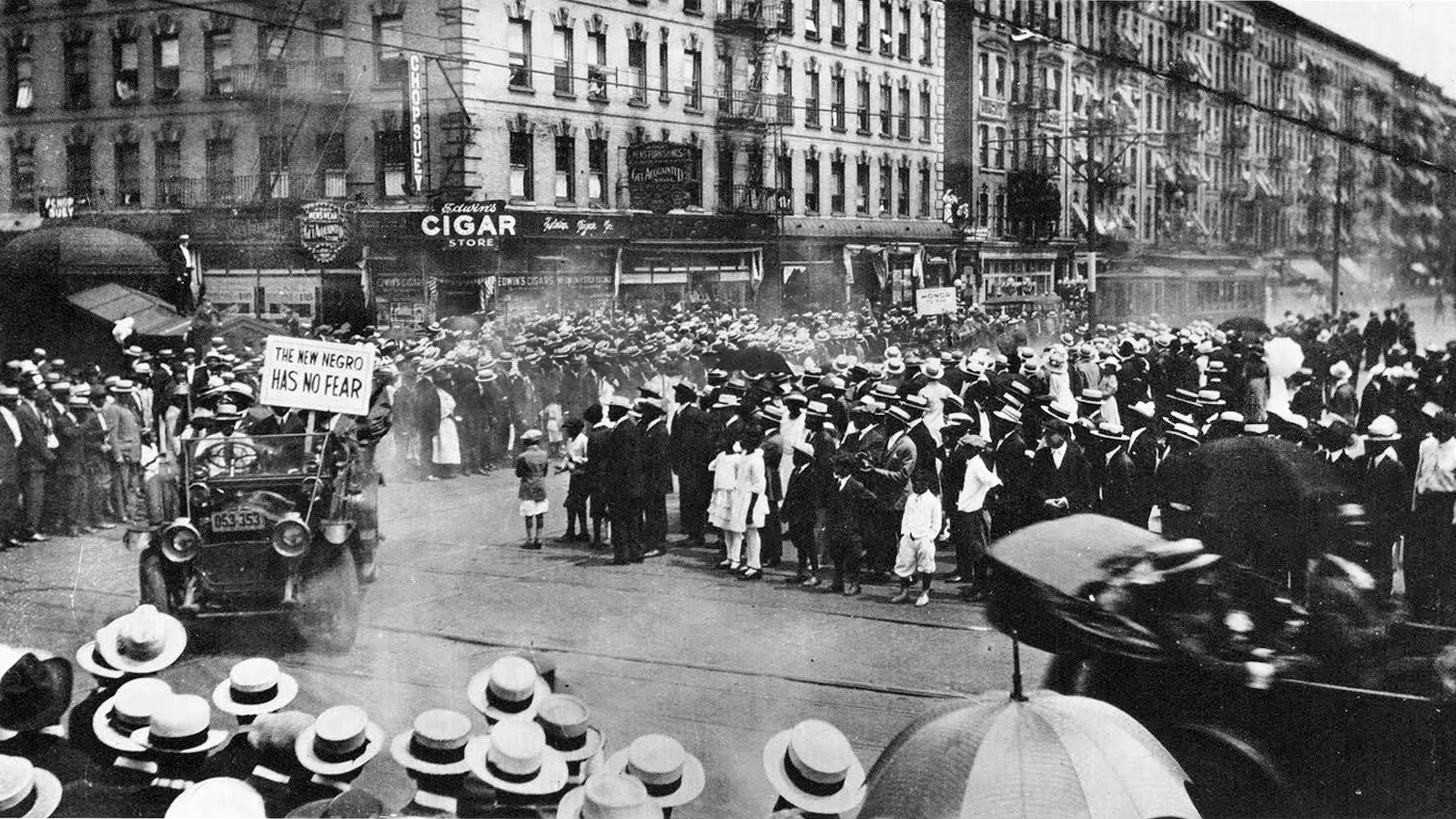 A UNIA parade through Harlem in 1920, with parade cars and crowds. One car displays a sign reading 'The New Negro Has No Fear.'